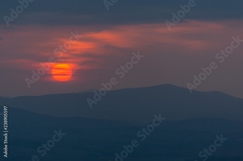 Mystic sunset in the Tuscany region with red solar disk and silhouettes of the hills, Italy