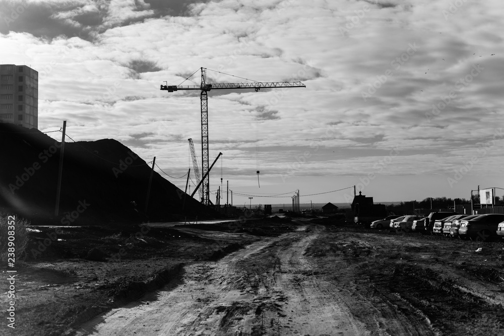 Fototapeta premium Widok placu budowy z dźwigami i wieżowcami mieszkalnymi. Czarno-białe zdjęcie
