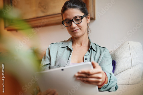 Casual attractive woman on couch at home with tablet
