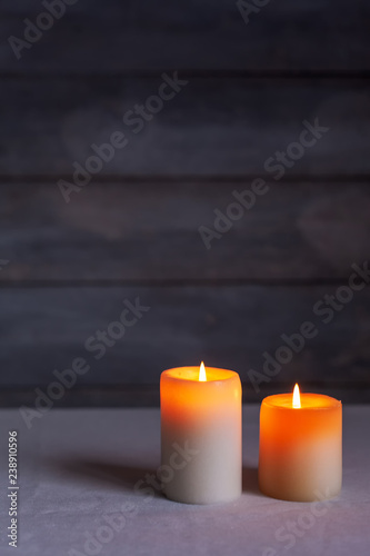 Close-up of Two lighted candles lit front view with rustic and vertical wood background