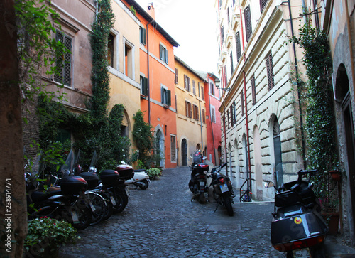 Photography Colorful, old, narrow alley in rome with parked scooters