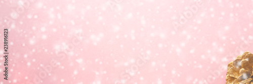 Christmas background with snow and golden pine cone on pink pastel table top view. Greeting card with space for text. Flat lay. ..