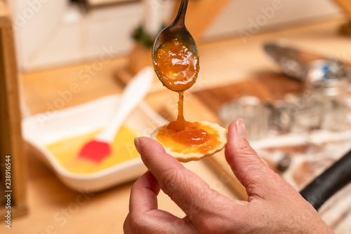 Marmelade auf Keks mit Löffel bestreichen
