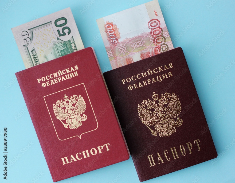 Russian money is 5,000 rubles, and Ameikans 50 dollars, a biometric passport and a passport of the Russian Federation on a colored background. The concept of travel abroad. Russian money is 5,000 rubles, and Ameikans 50 dollars, a biometric passport and a passport of the Russian Federation on a colored background. The concept of travel abroad.