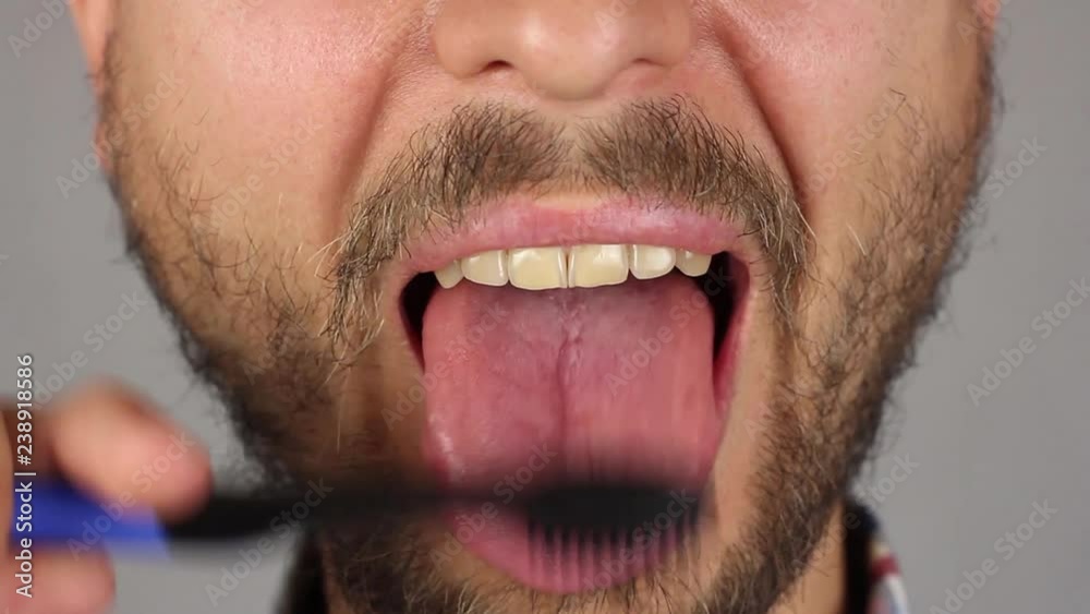 man with beard and mustache thoroughly brushes his tongue with black toothbrush, front view, massage and cleaning of plaque, closeup man with beard and mustache thoroughly brushes his tongue with black toothbrush, front view, massage and cleaning of plaque, closeup