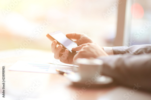 close up.the businessman uses a smartphone sitting at his Desk