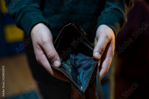 Young man holding the empty wallet , focus on the hand, conceptual image of underpaid work. photo