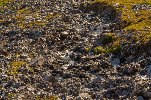 rocky mountain terrain with grass and a stream