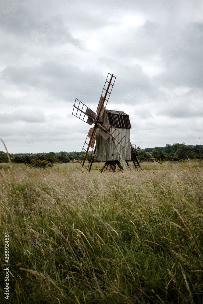 Naklejka premium Alte Windmühle aus Holz aus dem Feld. Düstere Stimmung. Dunkle Wolken