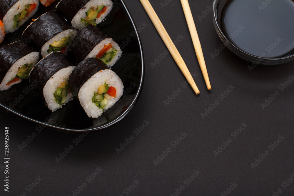 Sushi rolls in nori seaweed sheets and soy sauce on black background. Sushi rolls in nori seaweed sheets and soy sauce on black background.