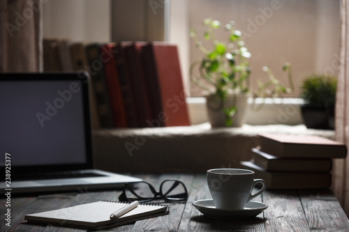 A cup of coffee in the workplace on a wooden table.