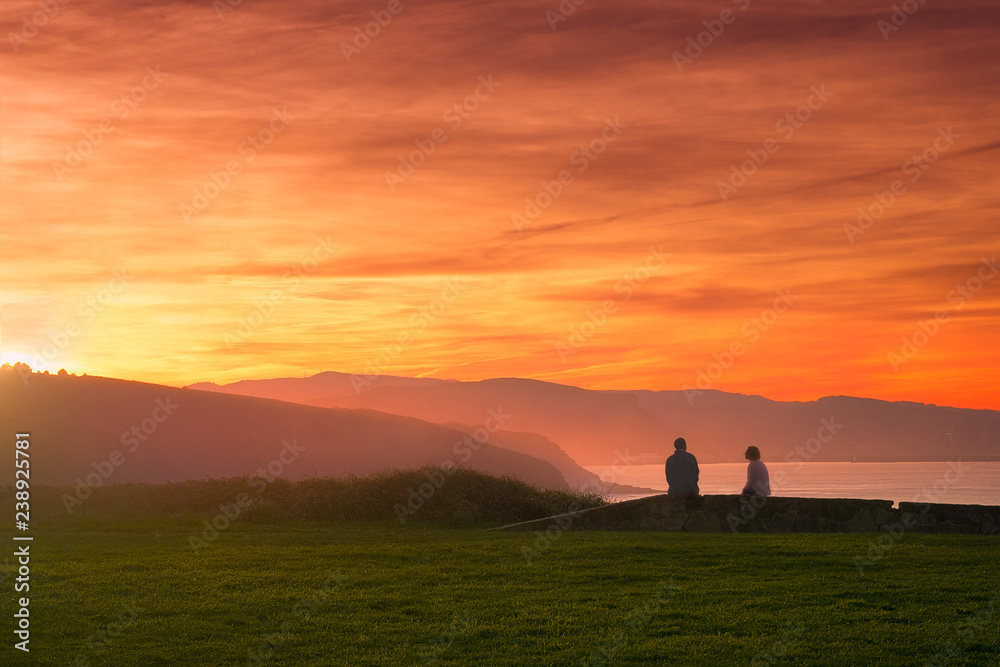 Couple watching beautiful sunset on the coast