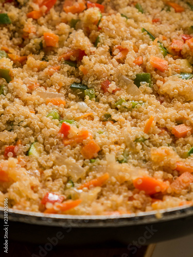 Mixing quinua with onion, red and green pepper and courgette in a frying pan. Cooking quinua with vegetables, recipe of quinua and vegetables