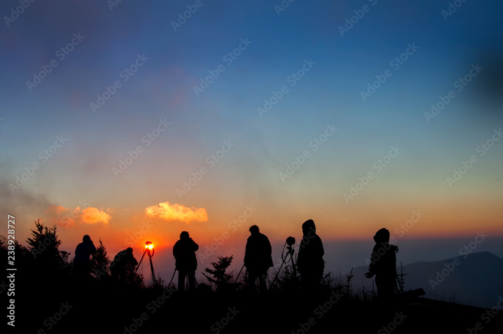 Photographers silhouetted against misty sunset on top of Mt. Mitchell in Appalachian Mountains in western North Carolina.