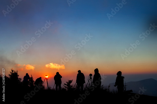 Photographers silhouetted against misty sunset on top of Mt. Mitchell in Appalachian Mountains in western North Carolina.