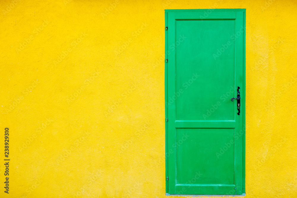 Single green doors on yellow wall, copy space