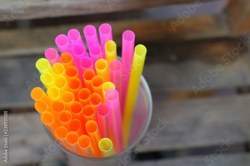 Top view of end of multicoloured plastic drinking straws in the glass, as sign for heterogeneity or teamwork. Environment about reject or reduce plastic drinking straws.