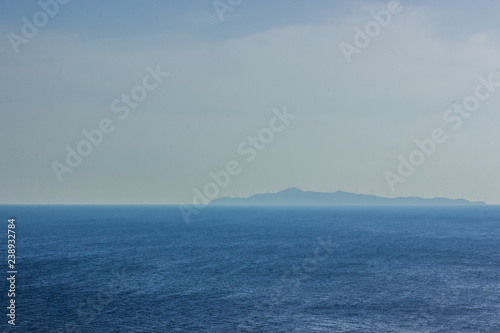 open sea nature scenery landscape and unfocused big island on horizon line background in morning sun rise foggy weather time, south wallpaper pattern concept with empty space for copy or text © Артём Князь