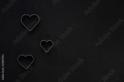 Metal hearts on a festive black background. Baking molds. Cookie cutters. Flat lay, top view
