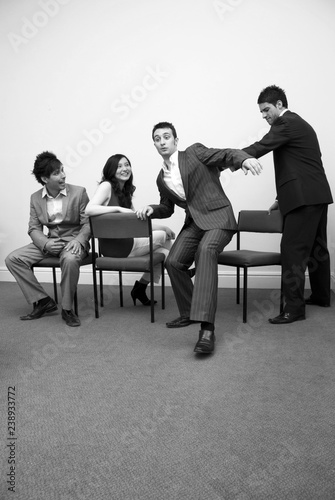 Stock photo of young business people playing musical chairs.