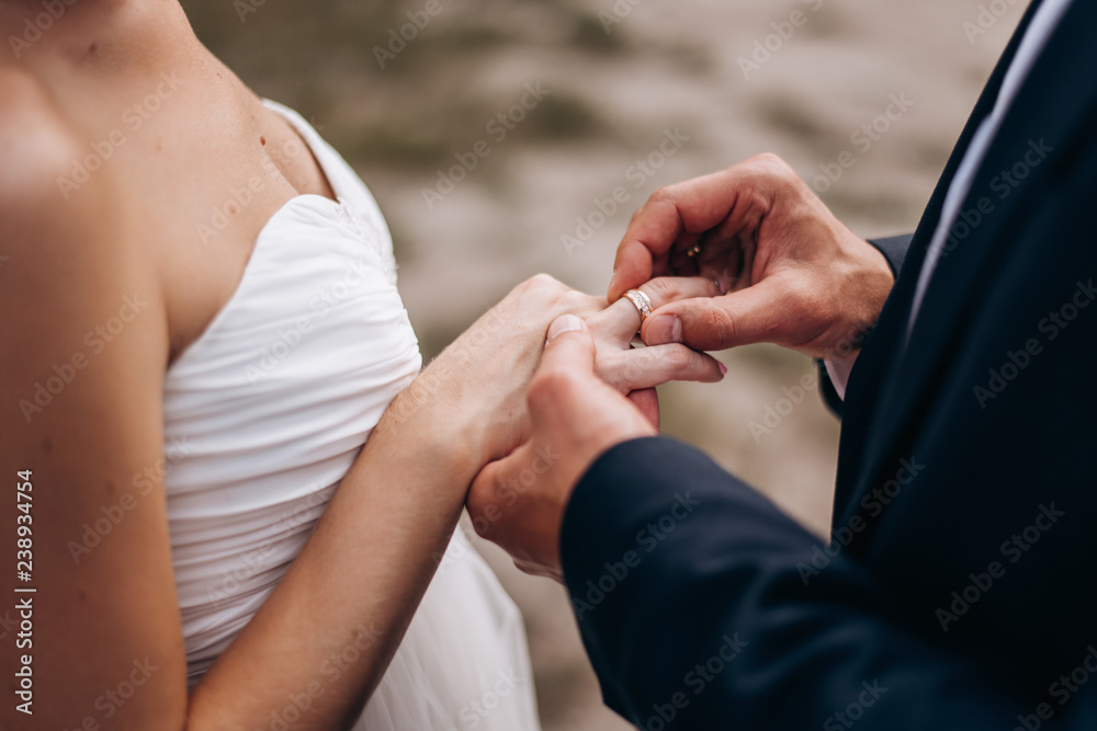 Fototapeta premium the groom wears a wedding ring on the bride's finger during the wedding ceremony