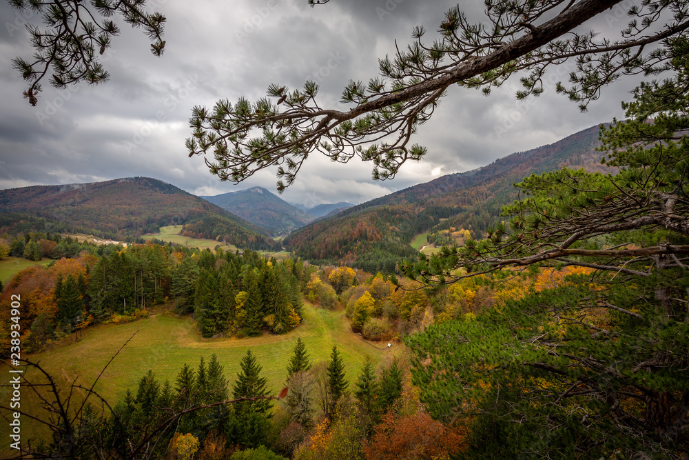 Scenic view from top of Hausstein to green valley of Muggendorf with colorful autumn forest and dramatic cloudy sky
