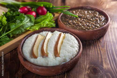 Mengrelian corn mamalica (ghomi) with cheese and lentls in ceramic dish (ketsi). Georgian traditional food photo