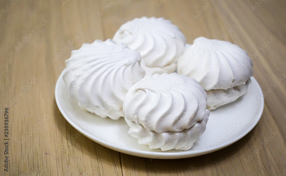 four zephyr (marshmallows) on a wooden table four zephyr (marshmallows) on a wooden table