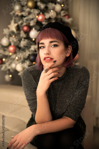 Young hipster woman sitting near Christmas tree