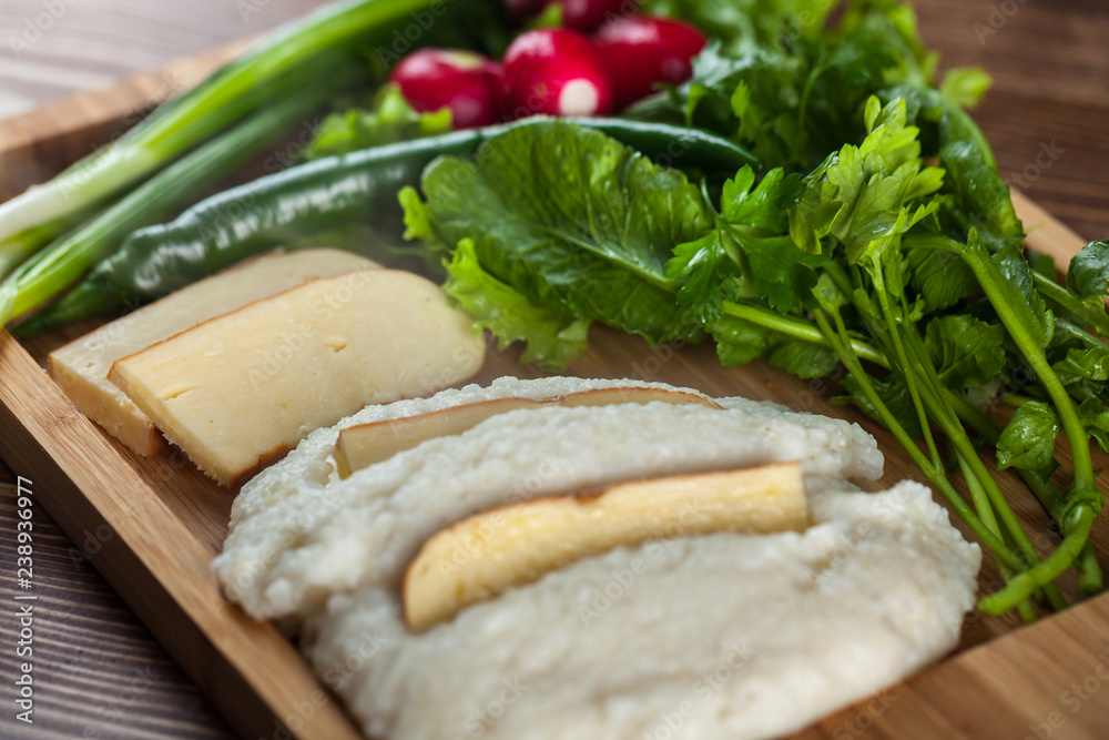 Mengrelian corn mamalica (ghomi) with cheese and various herb on wooden table. Georgian traditional food