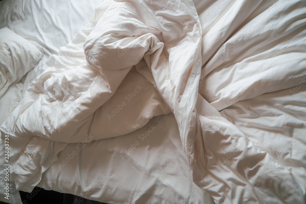 Morning Bliss: Unmade Bed with White Linen, Messy Pillow, and Cozy Blanket