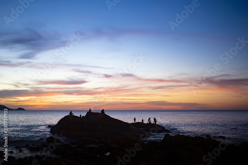 Silhouette of some people enjoying the beautiful sunset on a coast in Phuket, Thailand.