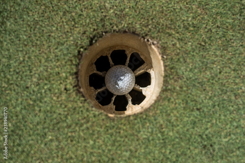 Golf field with white ball inside the hole