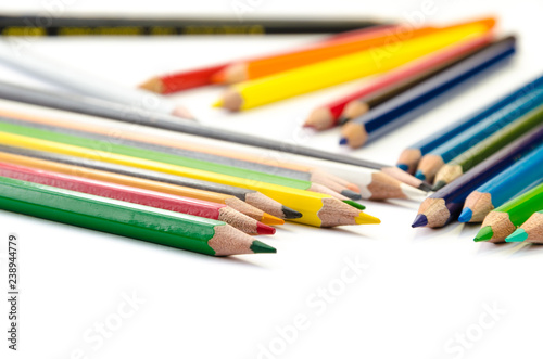 Color pencils pink light blue green yellow and red on white background.