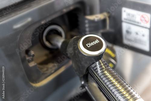 In a tank opening is a fuel nozzle with the inscription Diesel. Concept: diesel scandal or refueling
