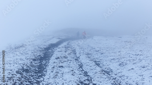 Two tourists go through the fog in the winter field © alexmu