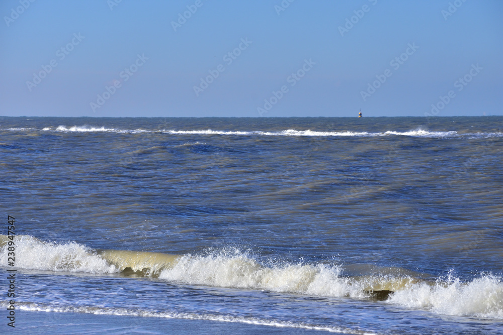 Morska fala z pianą atakuje piaszczystą plażę. - obrazy, fototapety, plakaty 