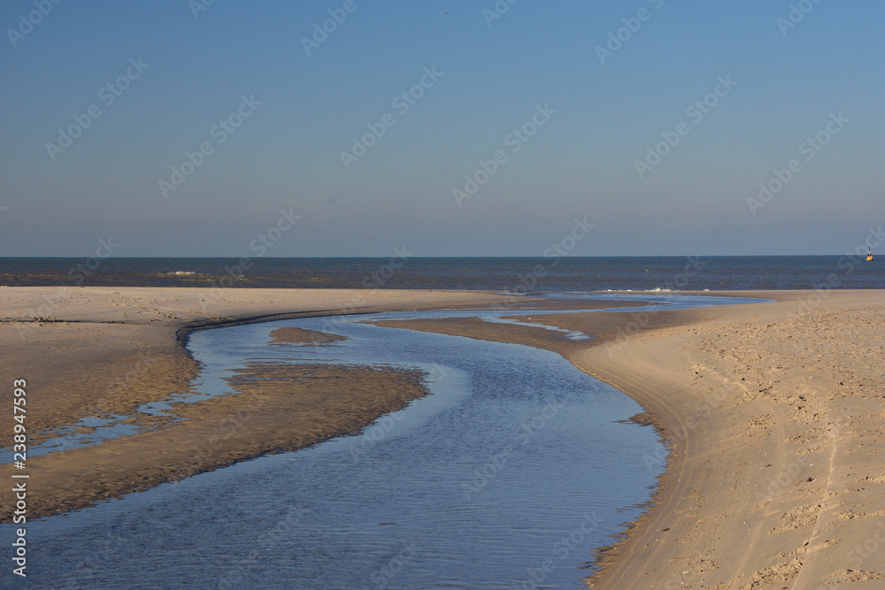 Piaszczysta plaża podczas odpływu pod bezchmurnym niebieskim niebem. Piaszczysta plaża podczas odpływu pod bezchmurnym niebieskim niebem.