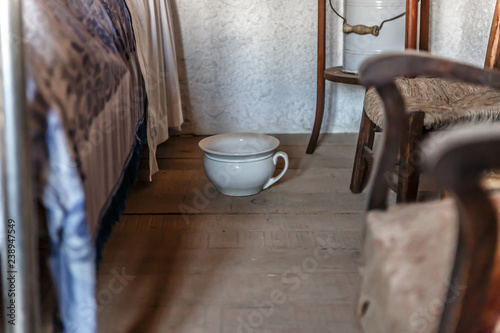 Old white urinal placed next to a bed in a bedroom in a house photo