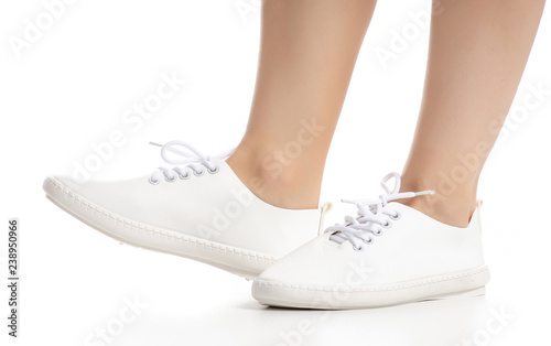 Female legs in white sneakers shoes beauty on white background. Isolation