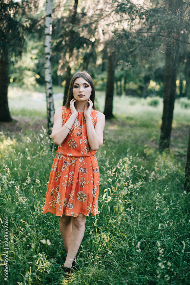 Beautiful young girl in a summer red dress in a park
