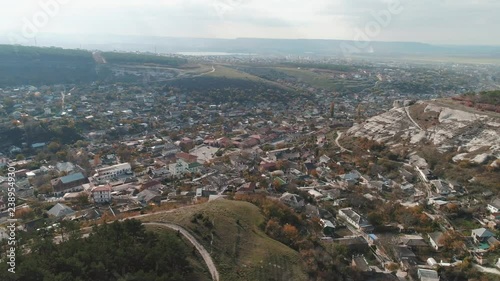 A city in lowland near the cliffs covered by pines. Shot. Aerial view photo