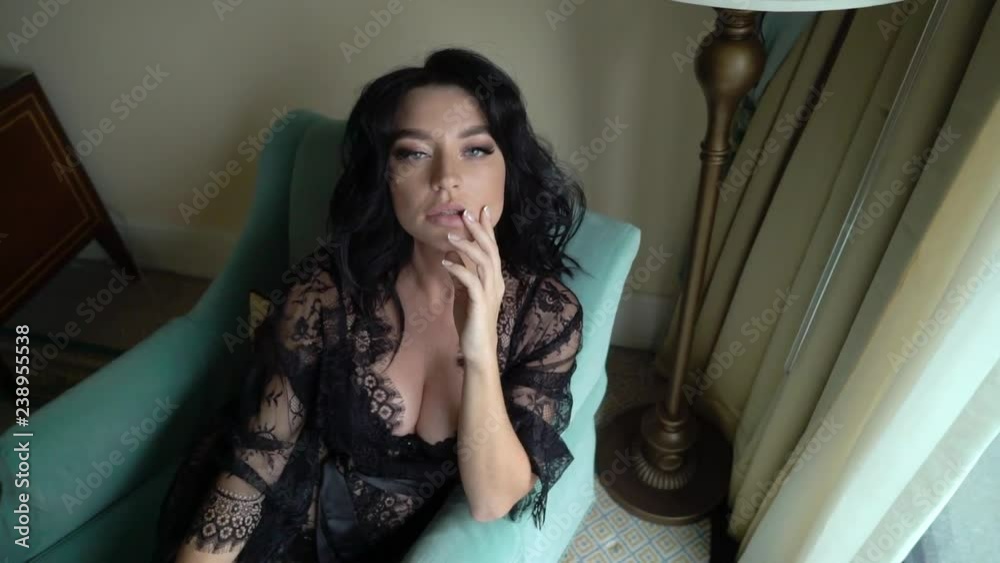 Young sexy brunette woman in lingerie sitting on chair in bedroom and posing. Flirting of lovely female in hotel room. Slowmotion. Touching herself lips Young sexy brunette woman in lingerie sitting on chair in bedroom and posing. Flirting of lovely female in hotel room. Slowmotion. Touching herself lips