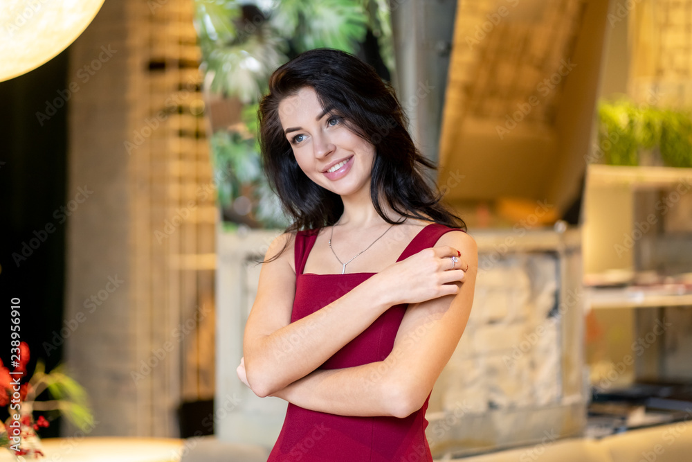 Fototapeta premium Pretty woman in red with long hair poses in cafe