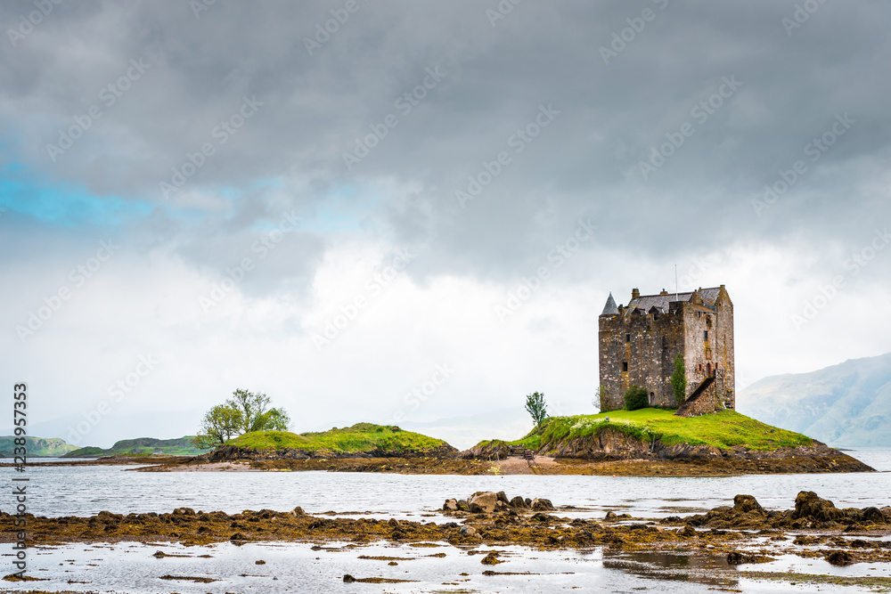 Mystical Castle Stalker on an islet on Loch Laich, cloudy day and low tide, scary and lost castle in Scotland, Great Britain