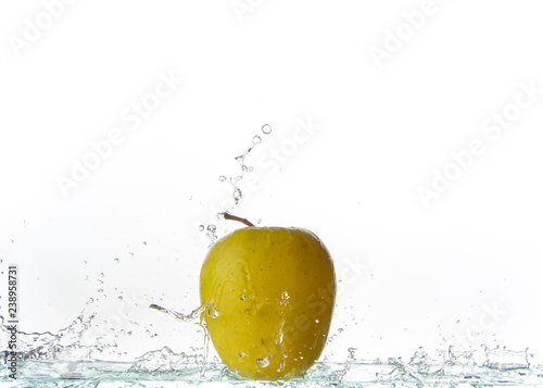 Green apple on a light background and splashing water