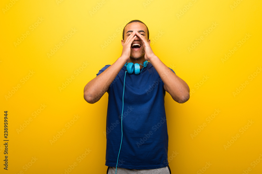 African american man with blue t-shirt on yellow background shouting and announcing something African american man with blue t-shirt on yellow background shouting and announcing something