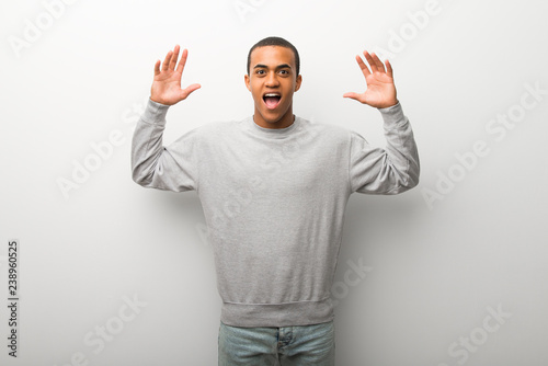 African american man on white wall background with surprise and shocked facial expression