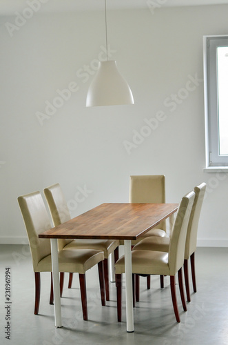 Dining table and chairs in the kitchen with lamp hanging over. © kyrychukvitaliy