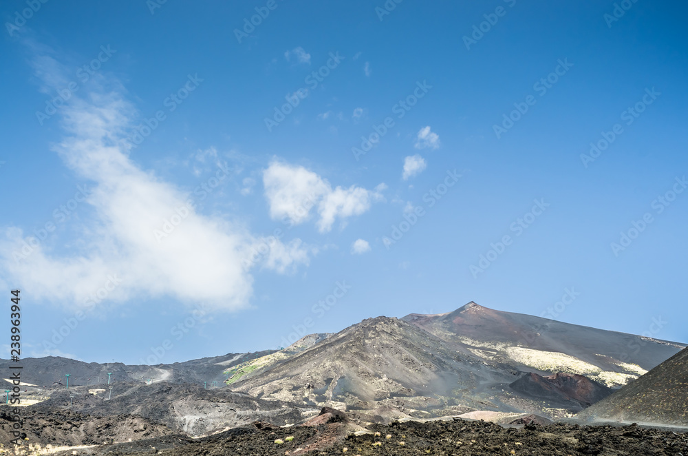 :  Panoramic view of volcano Etna against an intense blue sky. Horizontal view of the central crater. A row of people trying to climb to the summit